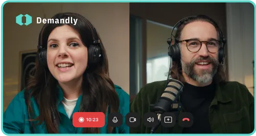 Two people wearing headsets smiling during an online video call with Demandly logo.
